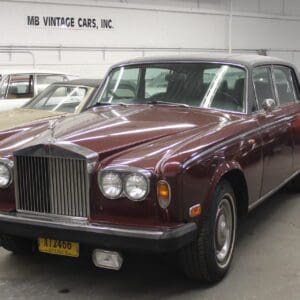 Vintage maroon car in showroom setting.